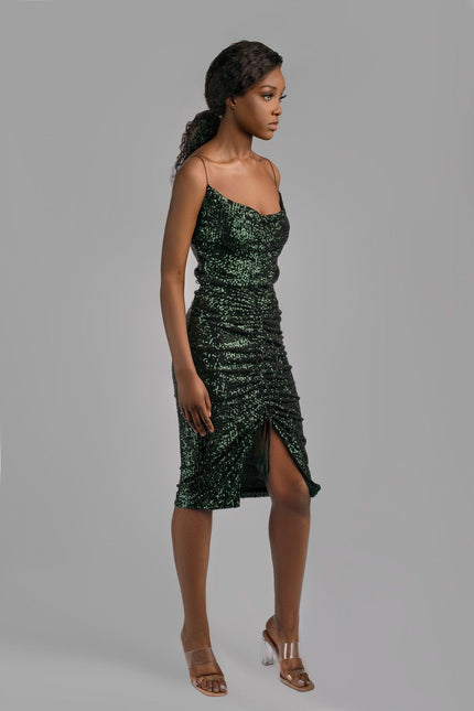 Girl wearing deep green spaghetti strap sequin top and matching sequin skirt with ruch details, posed against a light grey background. 