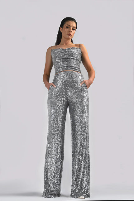 A woman wearing the TIA SEQUIN STRAIGHT LEG PANTS IN SILVER posed against a white background - ANITABEL