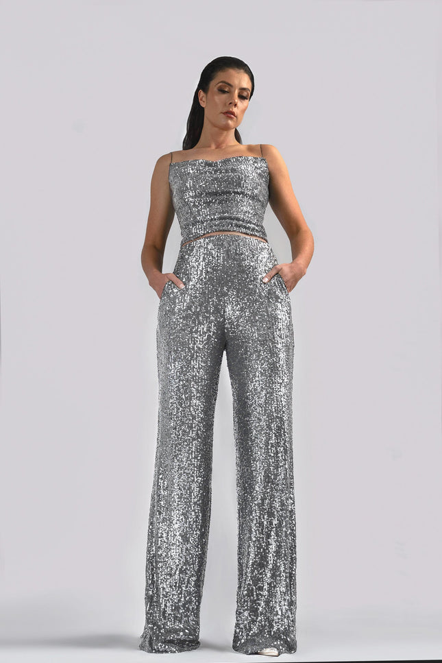 A woman wearing the TIA SEQUIN STRAIGHT LEG PANTS IN SILVER posed against a white background - ANITABEL