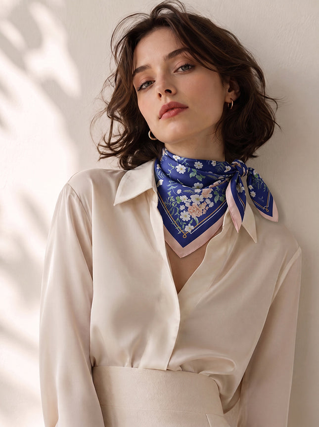 Chic model wearing a glaze blue and pink silk neck scarf styled with a classic triangle fold, exuding modern romanticism style.