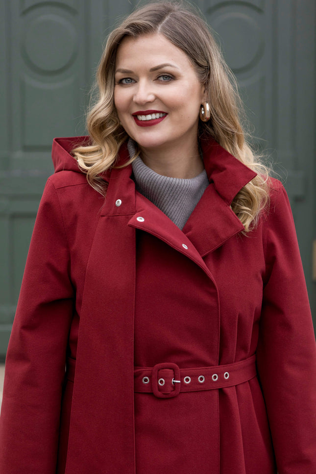 Long women’s winter coat in maroon shade, tailored for comfort and protection from the cold.